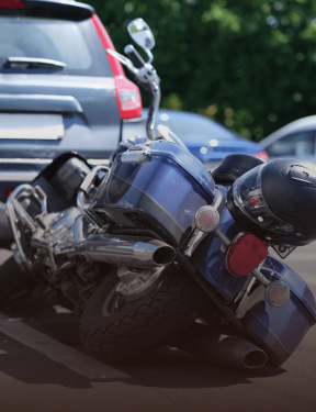 Motorcycle and helmets on the ground near a car.